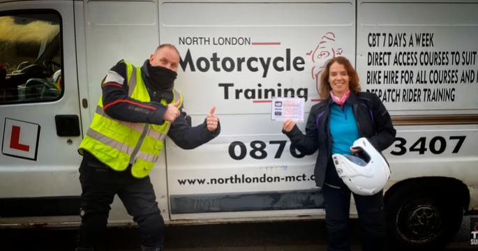 Motorcycle Training Blog Instructor and female trainee celebrating completion of CBT course outside North London Motorcycle Training van, with contact details visible.