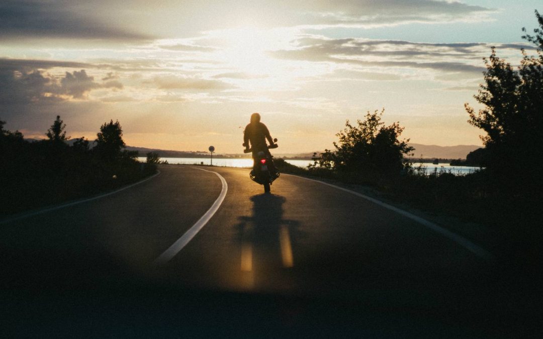 Motorcycle Training Blog Motorcyclist riding on a winding road at sunset, highlighting the challenges of visibility and awareness for motorcyclists.