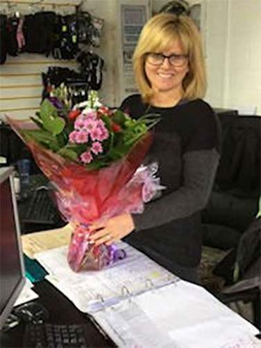 Woman holding a bouquet of flowers in an office setting at North London Motorcycle Training, showcasing the dedicated office team supporting motorcycle training.