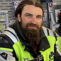 Bearded motorcycle instructor in vibrant safety gear, representing North London Motorcycle Training, showcasing dedication to motorcycle education.