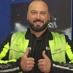 Man in a bright motorcycle jacket giving thumbs up, representing the dedicated staff at North London Motorcycle Training, highlighting their commitment to motorcycle training.